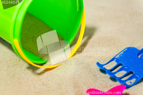 Image of close up of bucket and rake on beach sand