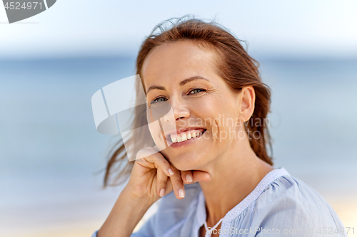 Image of portrait of happy smiling woman on summer beach