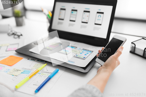 Image of web designer with smartphone and laptop at office