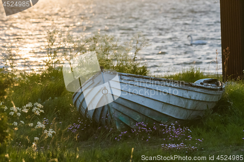 Image of Old white rowing boat on land by sunset