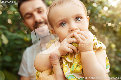 Image of The happy young family during picking apples in a garden outdoors