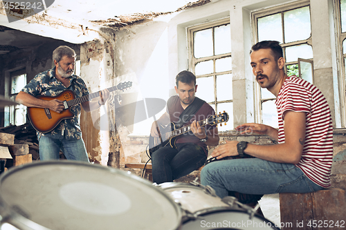 Image of Repetition of rock music band. Electric guitar player and drummer behind the drum set.