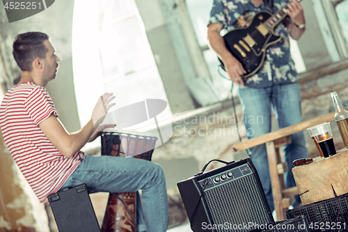 Image of Repetition of rock music band. Electric guitar player and drummer behind the drum set.