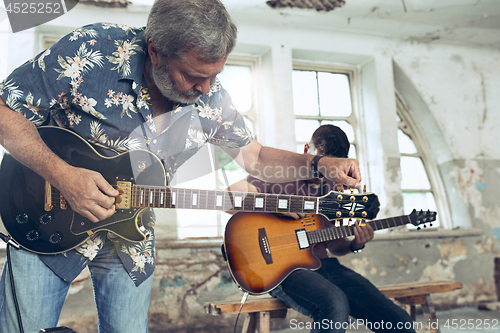 Image of Repetition of rock music band. Electric guitar player and drummer behind the drum set.