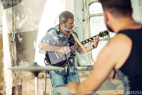 Image of Repetition of rock music band. Electric guitar player and drummer behind the drum set.