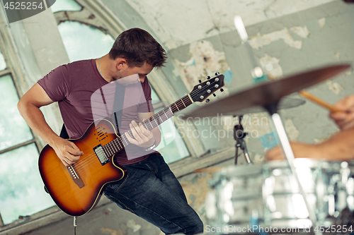 Image of Repetition of rock music band. Electric guitar player and drummer behind the drum set.