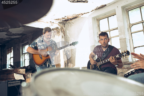 Image of Repetition of rock music band. Electric guitar player and drummer behind the drum set.