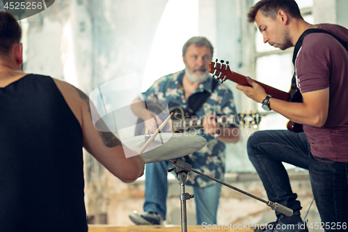 Image of Repetition of rock music band. Electric guitar player and drummer behind the drum set.