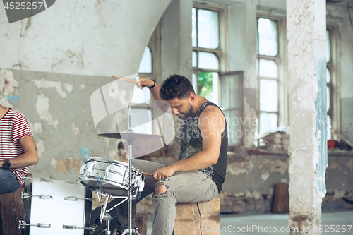 Image of Repetition of rock music band. Electric guitar player and drummer behind the drum set.