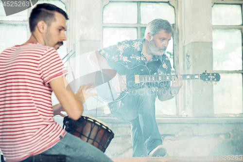 Image of Repetition of rock music band. Electric guitar player and drummer behind the drum set.