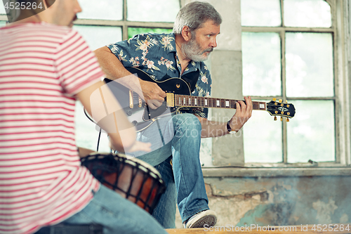 Image of Repetition of rock music band. Electric guitar player and drummer behind the drum set.