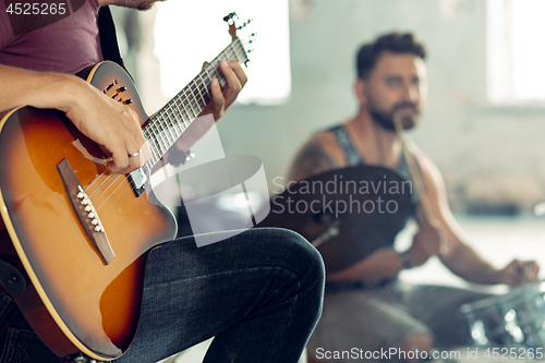 Image of Repetition of rock music band. Electric guitar player and drummer behind the drum set.