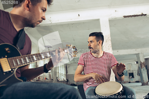 Image of Repetition of rock music band. Electric guitar player and drummer behind the drum set.