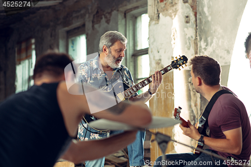 Image of Repetition of rock music band. Electric guitar player and drummer behind the drum set.