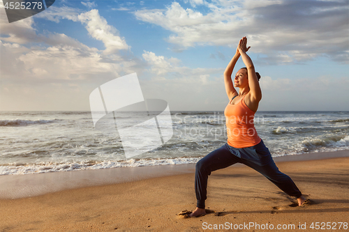 Image of Woman doing yoga asana Virabhadrasana 1 Warrior Pose on beach on