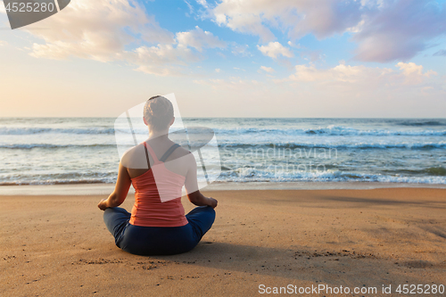 Image of Young sporty fit woman doing yoga oudoors at beach