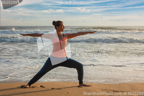 Image of Woman doing yoga asana Virabhadrasana 1 Warrior Pose on beach on