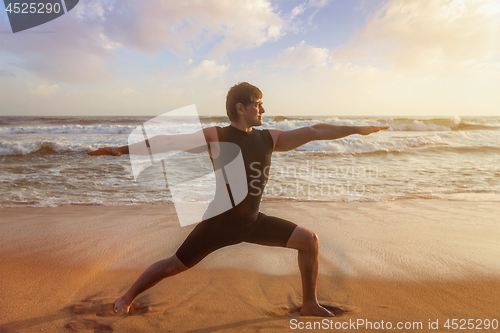 Image of Man doing yoga asana Virabhadrasana 1 Warrior Pose on beach