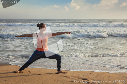 Image of Woman doing yoga asana Virabhadrasana 1 Warrior Pose on beach on