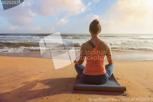 Image of Woman doing yoga oudoors at beach - Padmasana lotus pose