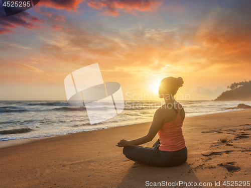 Image of Young sporty fit woman doing yoga oudoors at beach