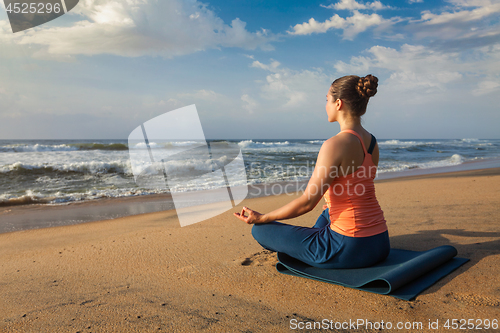 Image of Woman doing yoga Lotus pose oudoors at beach