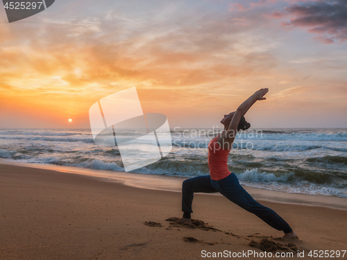 Image of Woman doing yoga asana Virabhadrasana 1 Warrior Pose on beach on