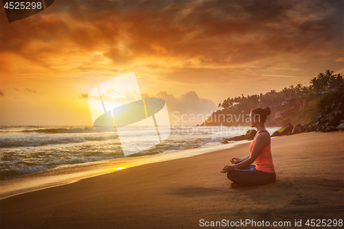 Image of Young sporty fit woman doing yoga oudoors at beach