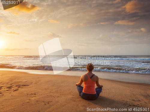 Image of Young sporty fit woman doing yoga oudoors at beach