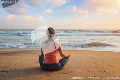 Image of Woman doing yoga Lotus pose oudoors at beach