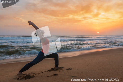 Image of Woman doing yoga asana Virabhadrasana 1 Warrior Pose on beach on