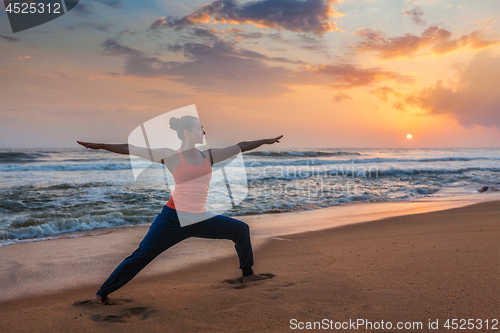 Image of Woman doing yoga asana Virabhadrasana 1 Warrior Pose on beach on