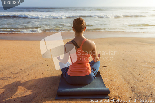 Image of Woman doing yoga Lotus pose oudoors at beach