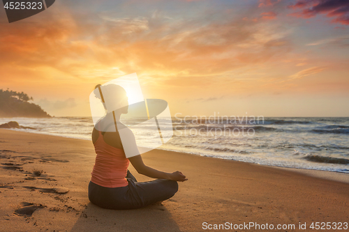 Image of Woman doing yoga oudoors at beach - Padmasana lotus pose