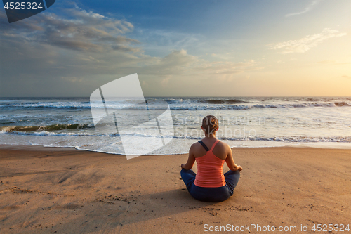 Image of Woman doing yoga oudoors at beach - Padmasana lotus pose