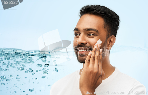 Image of happy indian man applying cream to face