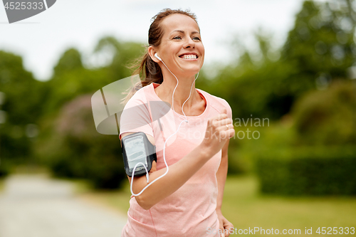 Image of woman with earphones add armband jogging at park