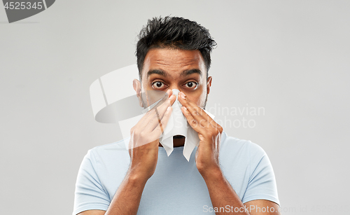 Image of indian man with paper napkin blowing nose