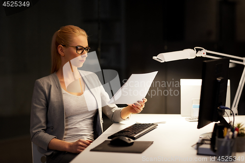 Image of businesswoman with papers working at night office