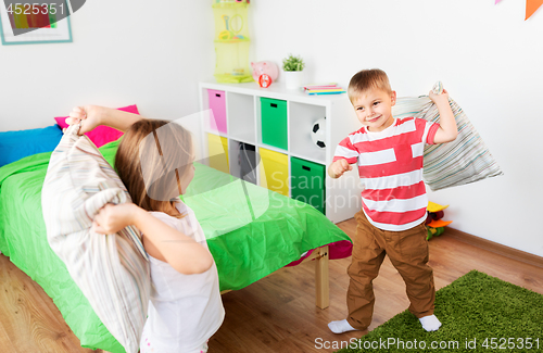 Image of children playing and fighting by pillows at home
