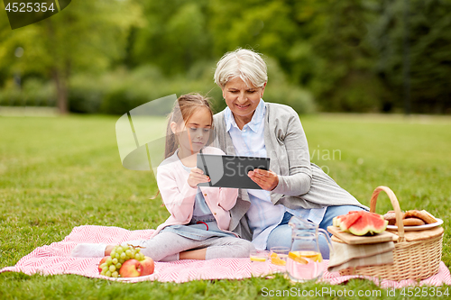 Image of grandmother and granddaughter with tablet at park