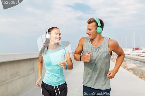Image of couple with headphones running outdoors