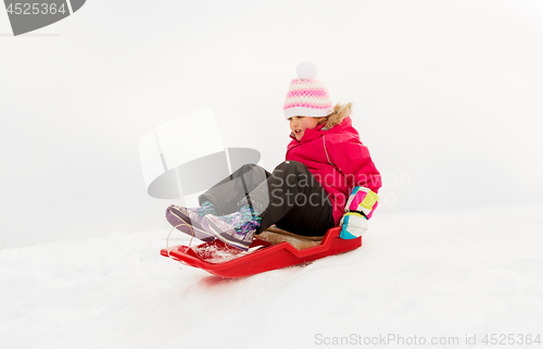 Image of happy little girl sliding down on sled in winter