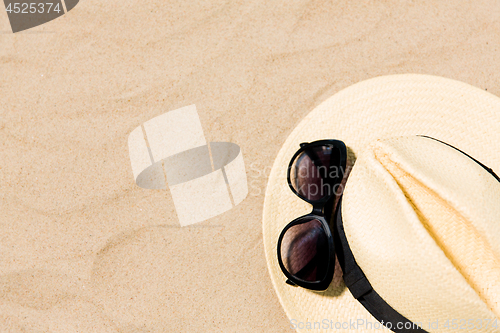 Image of straw hat and sunglasses on beach sand