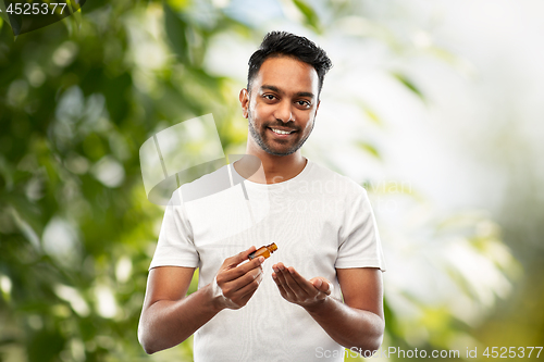 Image of indian man applying grooming oil to his hand