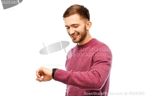 Image of smiling young man checking time on wristwatch