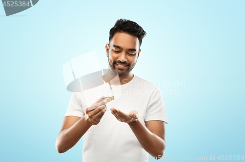 Image of indian man applying grooming oil to his hand