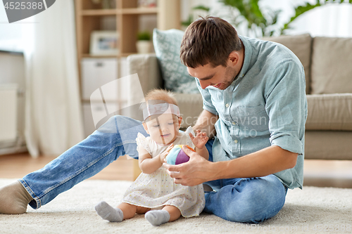 Image of father and little baby daughter with ball at home
