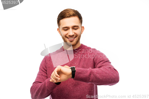 Image of smiling young man checking time on wristwatch