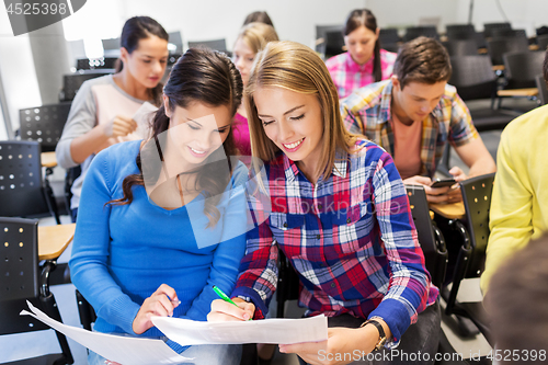 Image of happy student girls with tests at lecture hall